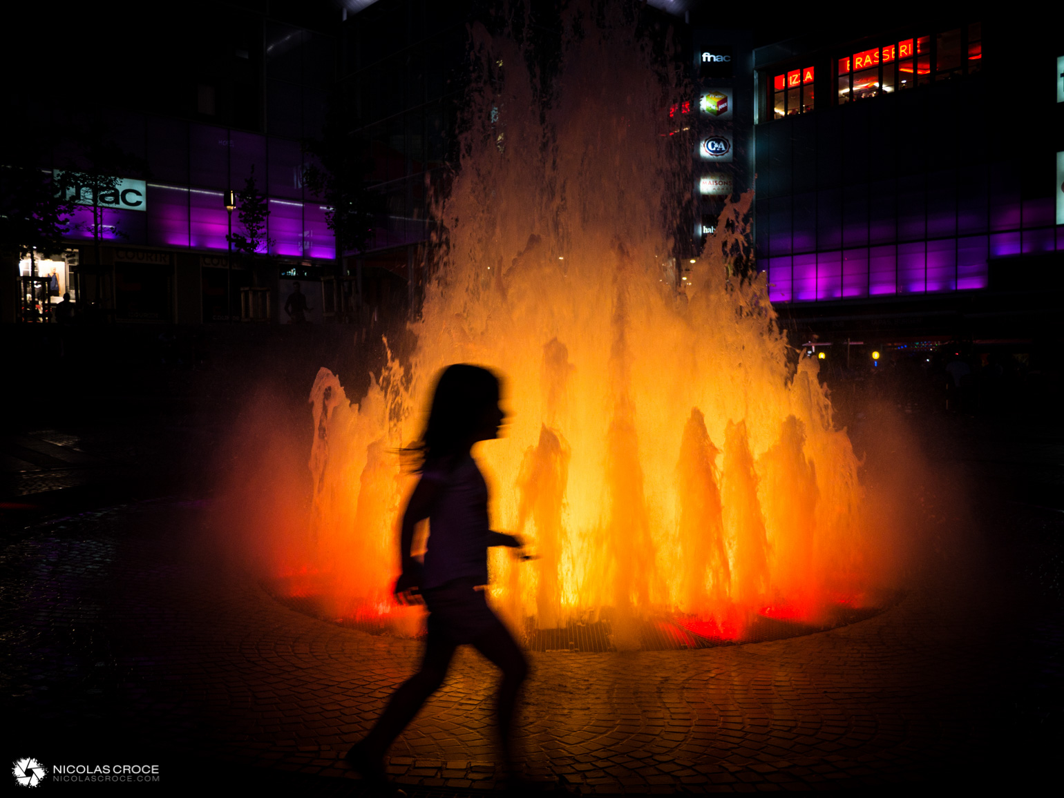 Un enfant joue devant la fontaine de la place de Jaude, qui simule un volcan en éruption