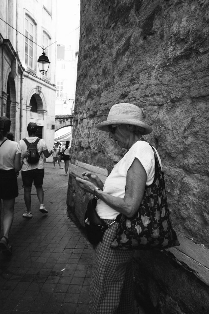 Une femme au chapeau lit contre un mur de pierre, en noir et blanc