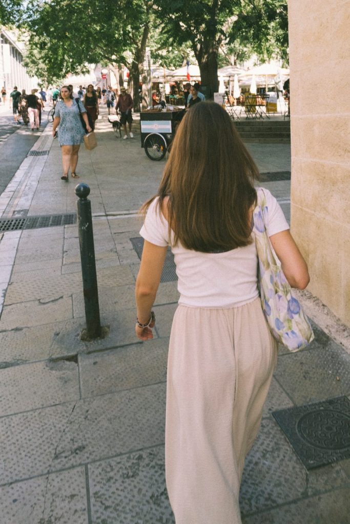 Une jeune femme de dos dans une rue piétonne ensoleillée