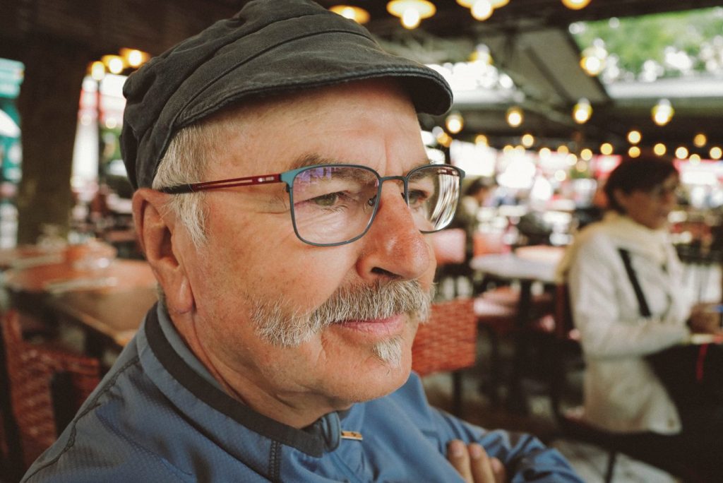Portrait d'un homme à la casquette et à la moustache blanche, à une terrasse