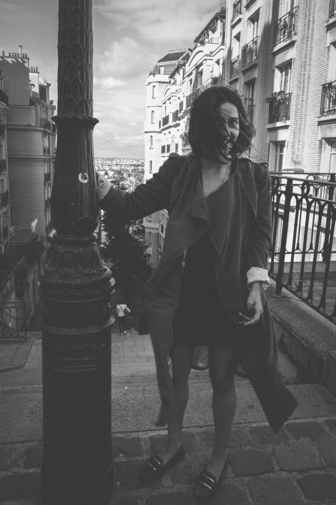 Une femme appuyée contre un lampadaire dans une rue de Paris, en noir et blanc