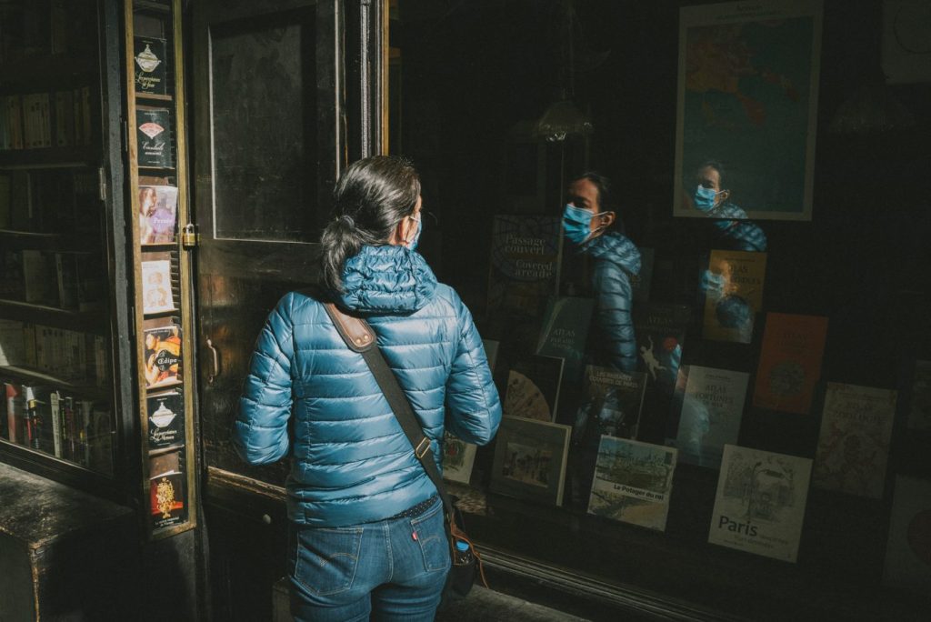 Une passante en doudoune bleue devant une vitrine de galerie